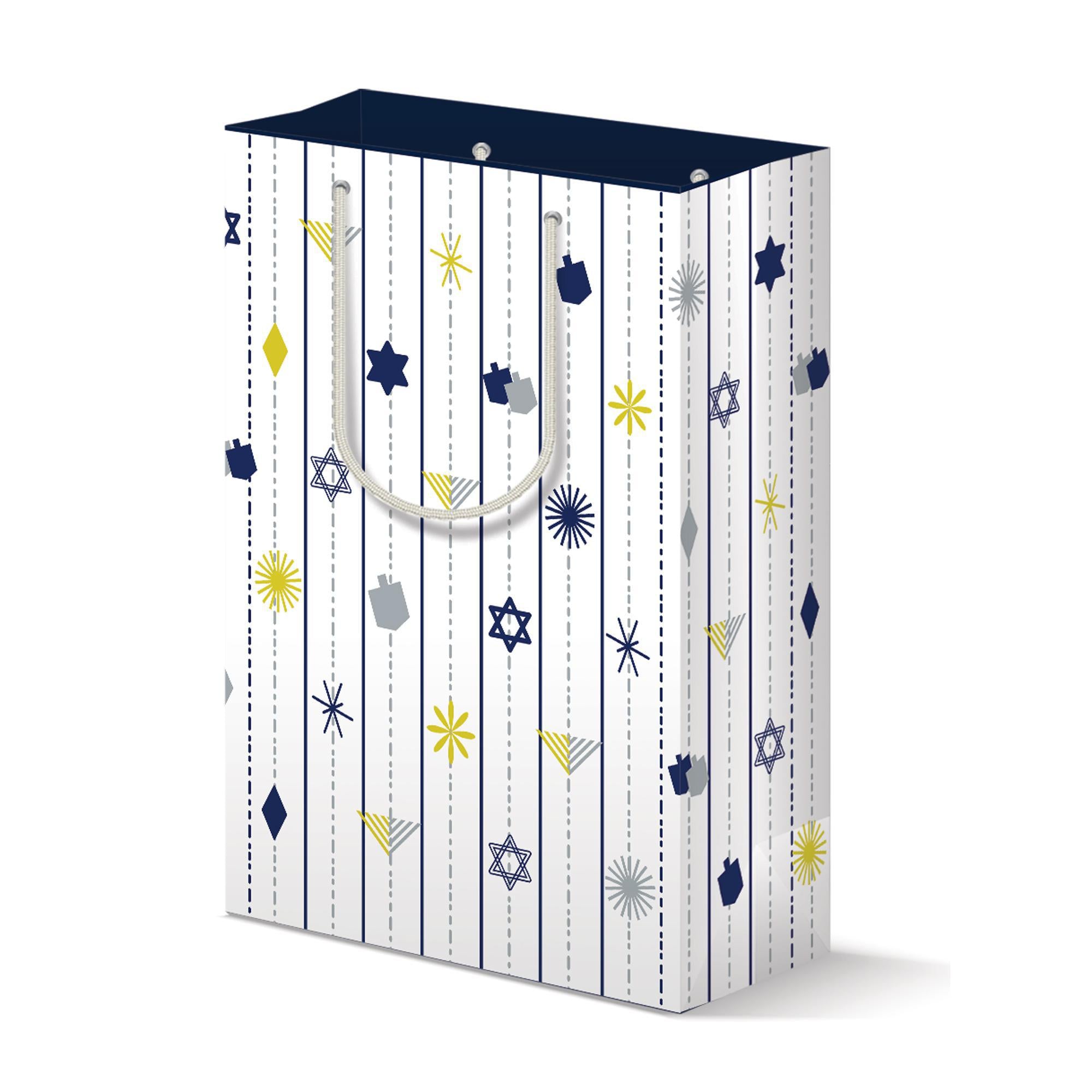 Modern Hanukkah gift bag with white background featuring vertical lines of blue, yellow, and silver dreidels, menorahs, Stars of David, and abstract shapes. Navy blue top and silver rope handles complete the festive design.