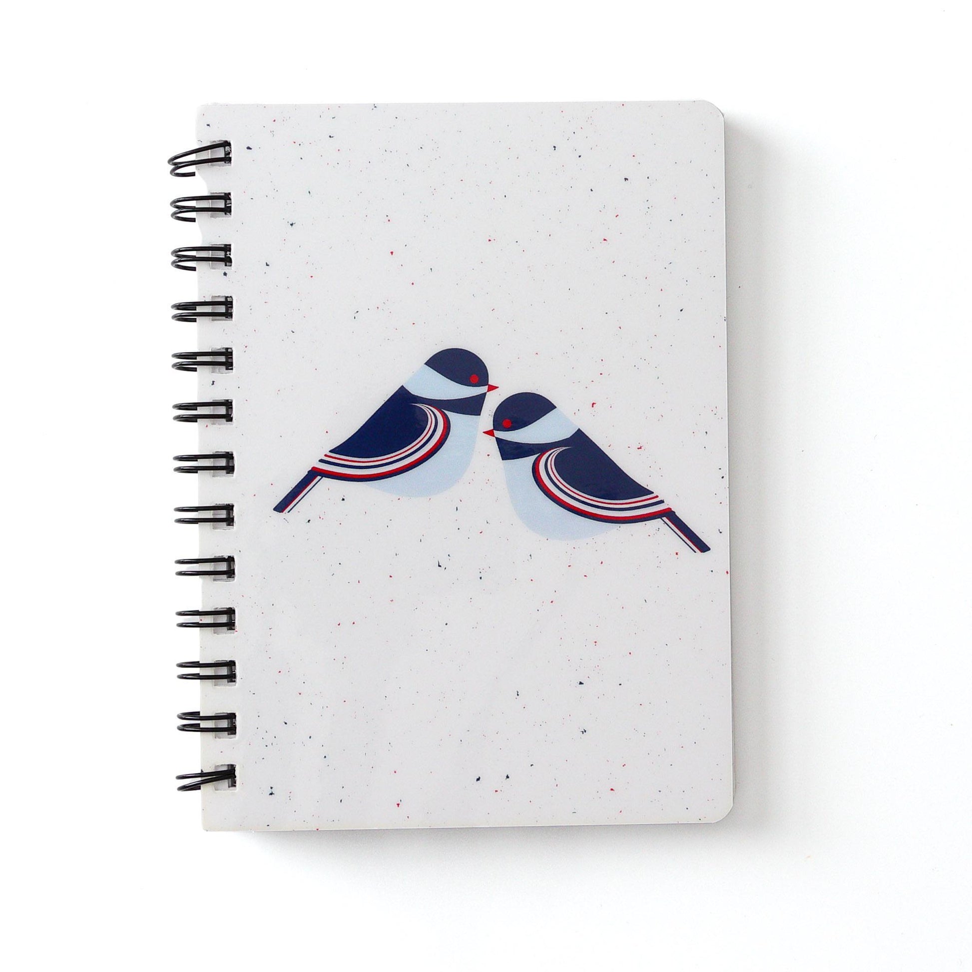 Spiral-bound notebook with white cover featuring stylized illustration of two chickadees in navy blue, red, and light blue on speckled background. 5x7 inch size for portable writing and note-taking.