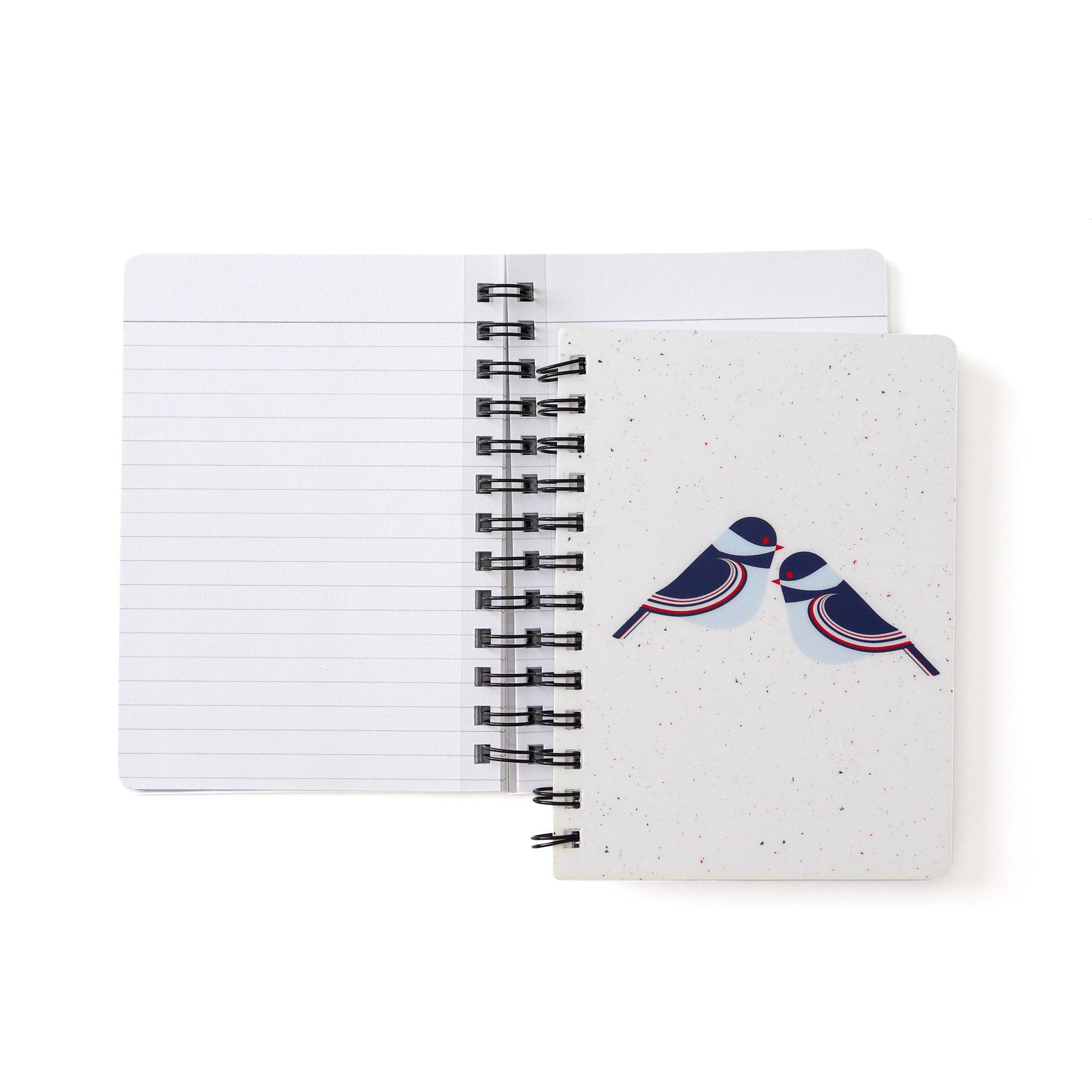 Spiral-bound notebook with modern chickadee design on cover, open to show lined pages inside. White background with stylized blue and red birds on front.