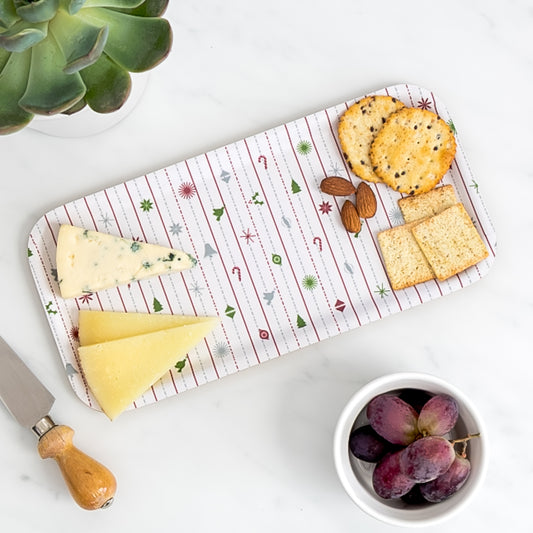 Cheese board of assorted cheese and crackers on birch tray with Christmas pattern