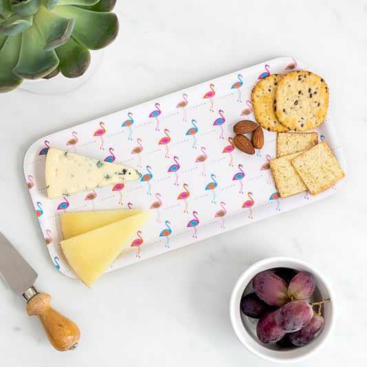 Cheese board of assorted cheese and crackers on birch tray with retro flamingo pattern