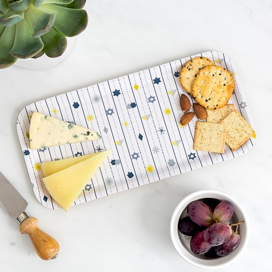 Cheese board of assorted cheese and crackers on birch tray with Hanukkah pattern