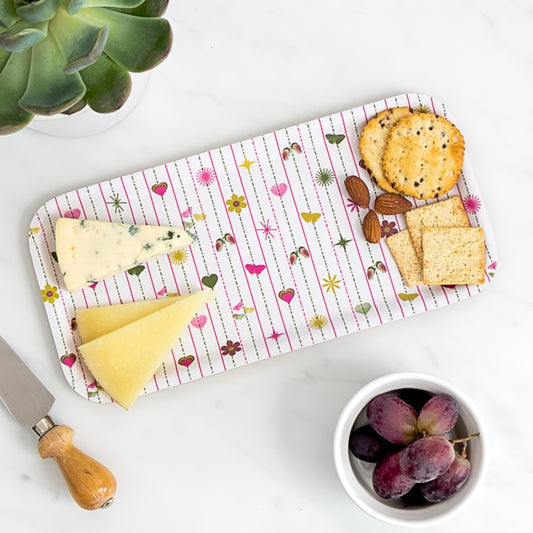 Cheese board of assorted cheese and crackers on birch tray with pink heart pattern