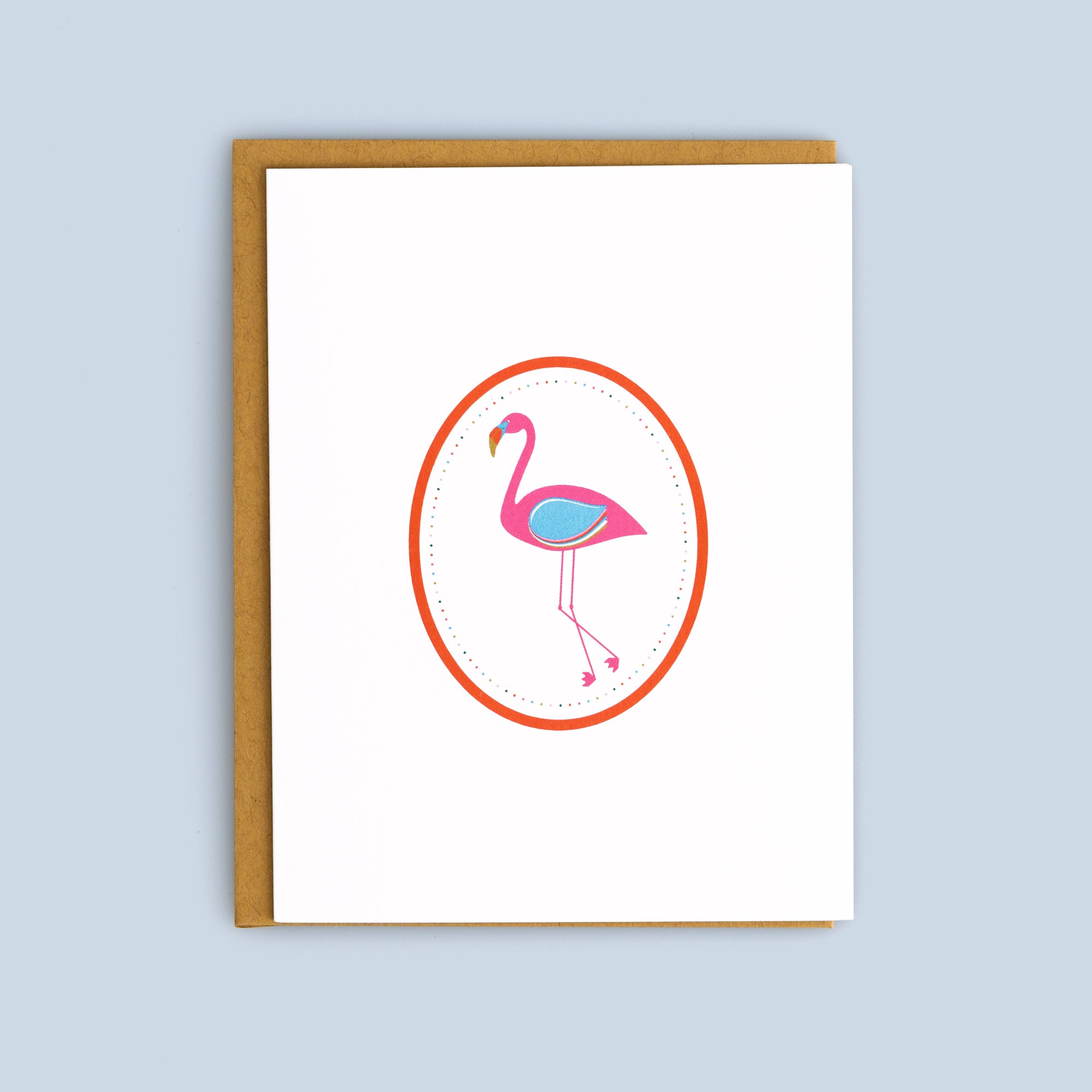 Flat card featuring a pink flamingo inside a red oval frame with a kraft envelope on a light blue background