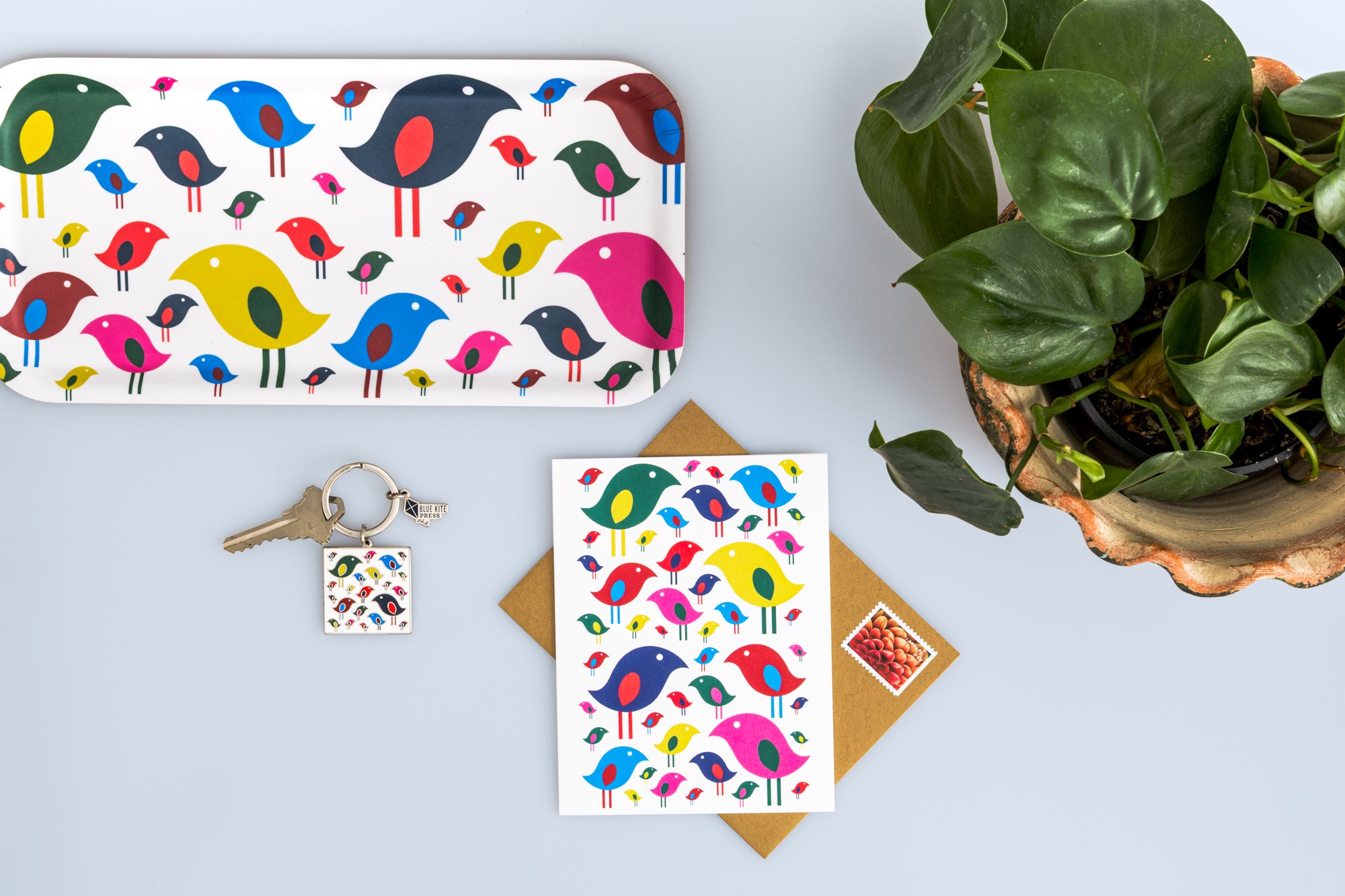 Blue Kite Press bright birds tray, keychain and card on desk with plant. 