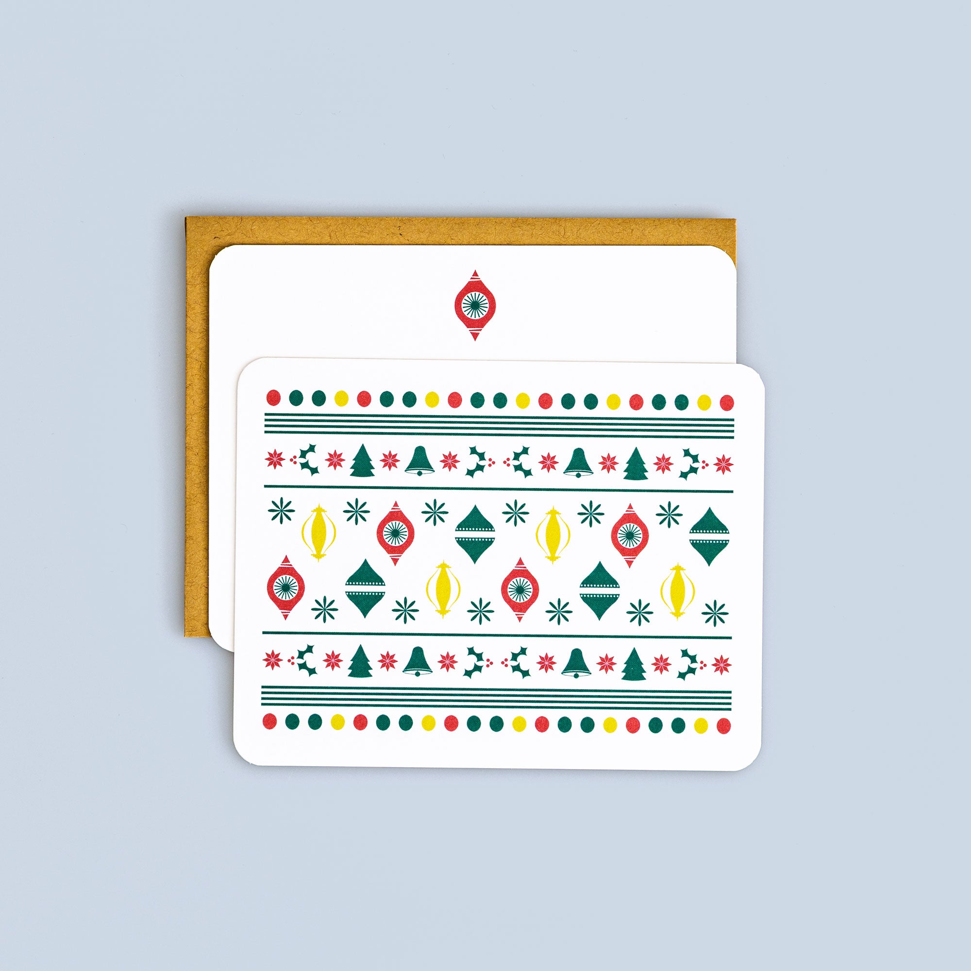 Flat Christmas card with vintage ornament pattern in red, green, and yellow with coordinating kraft envelope on blue background