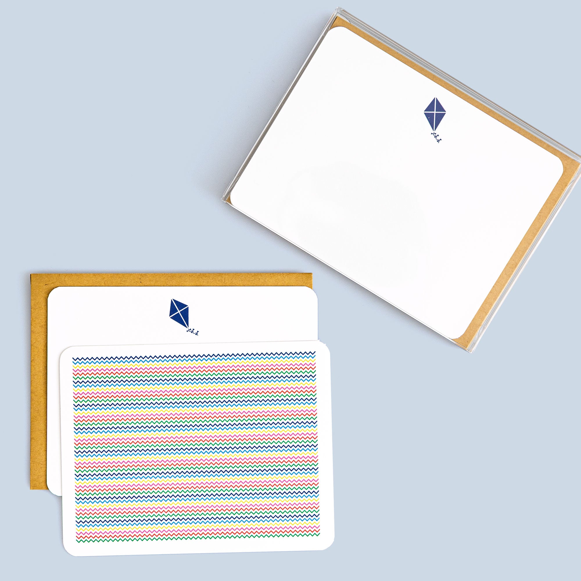 Set of flat cards featuring colorful zig zag patterns and a small blue kite illustration with kraft envelopes