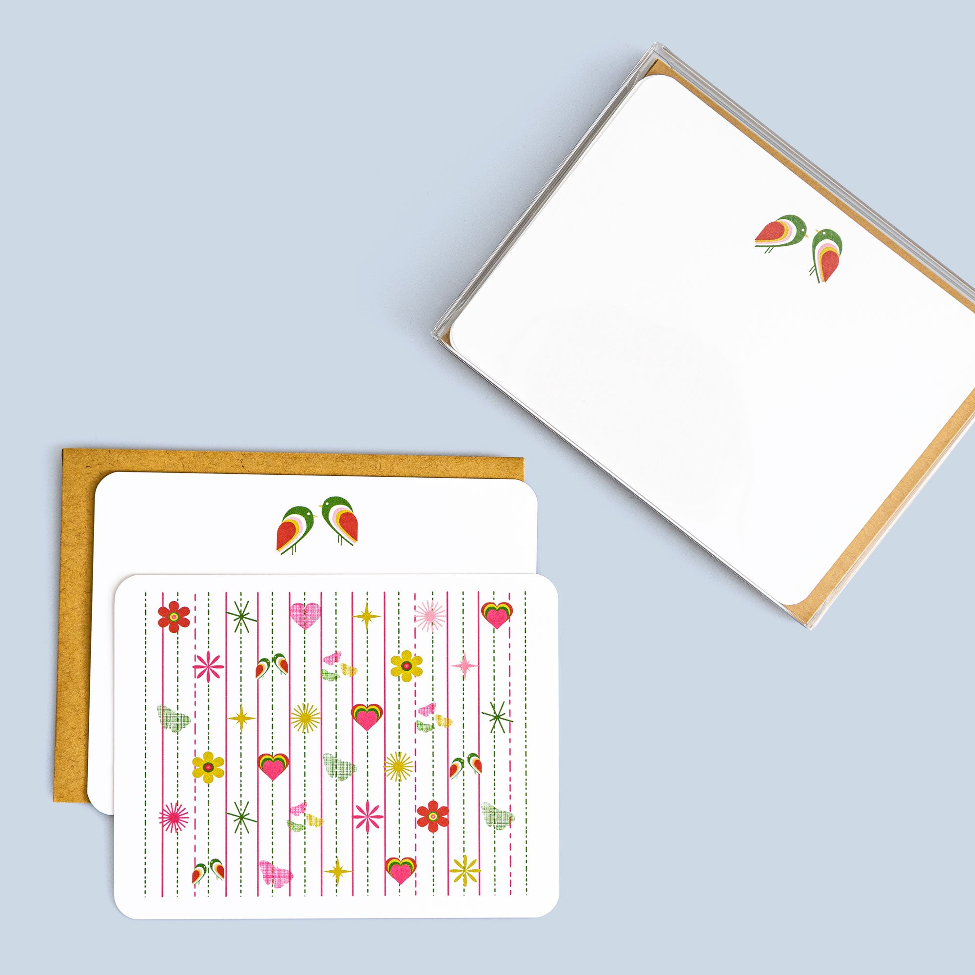 Box set of 8 flat pink tiki cards with bird and floral pattern, includes coordinating kraft envelopes on light blue background
