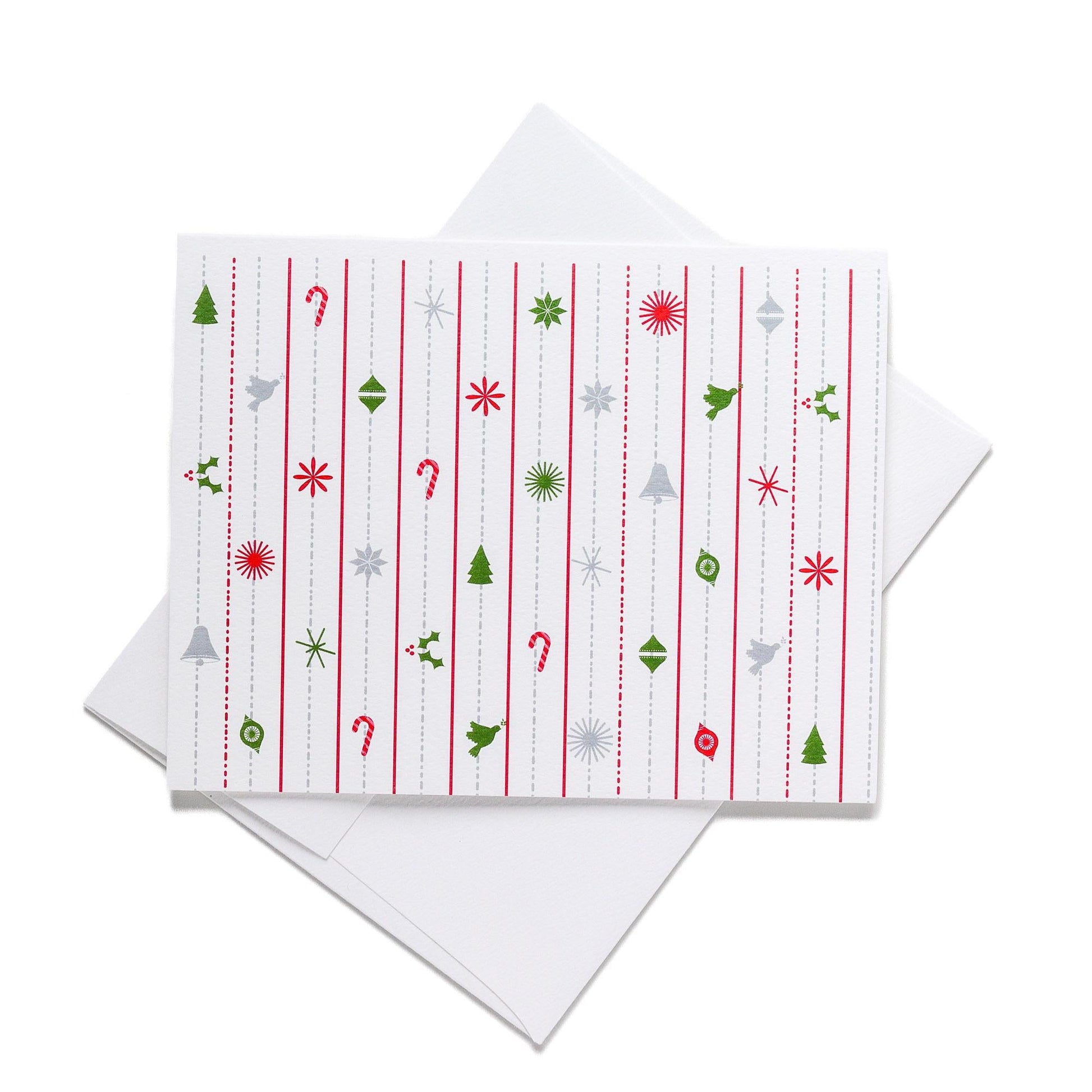 Modern Christmas card with white background featuring vertical red dotted lines and colorful festive icons including trees, ornaments, snowflakes, candy canes, and holly. Card shown with white envelope.